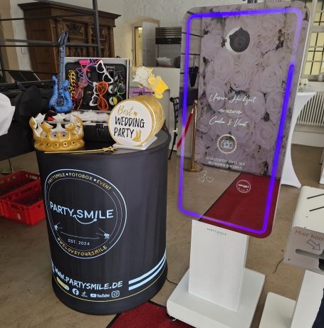 Stand mit Partydeko, inkl. einer Krone, einem Schild und einem Smartphone-Display.