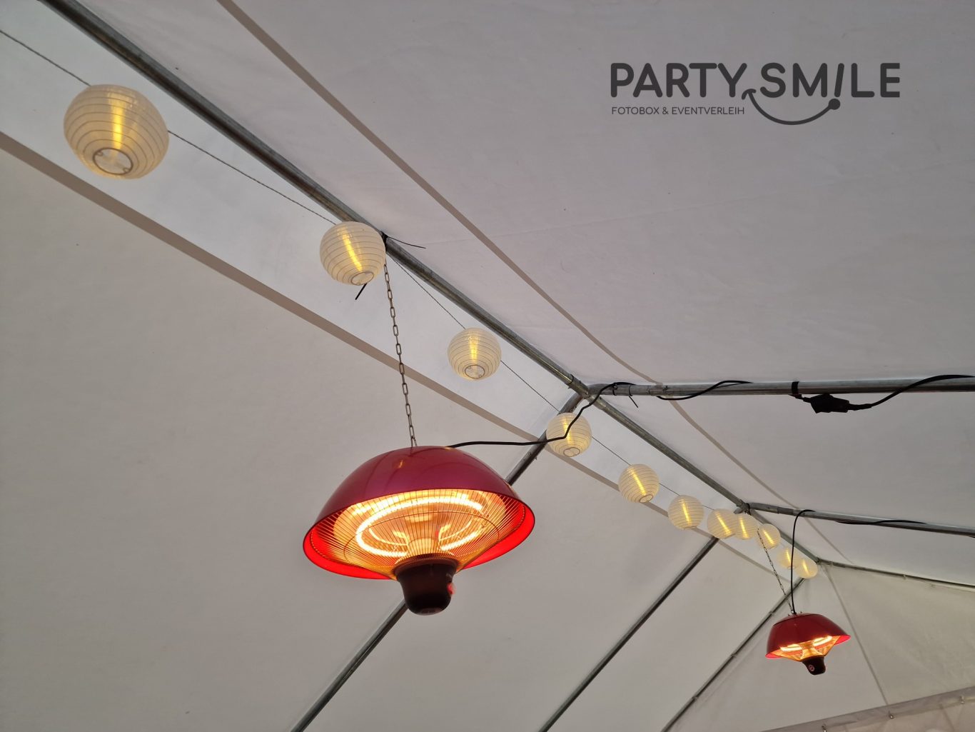 Heizstrahler hängend Rote Lampenschirme hängen unter einem Zelt mit Lichterkette.