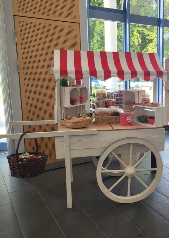 Ein Verkaufswagen mit roten und weißen Streifen, gefüllt mit Snacks und Getränken.